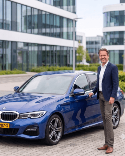 Hero photo — ondernemer naast zijn blauwe sedan